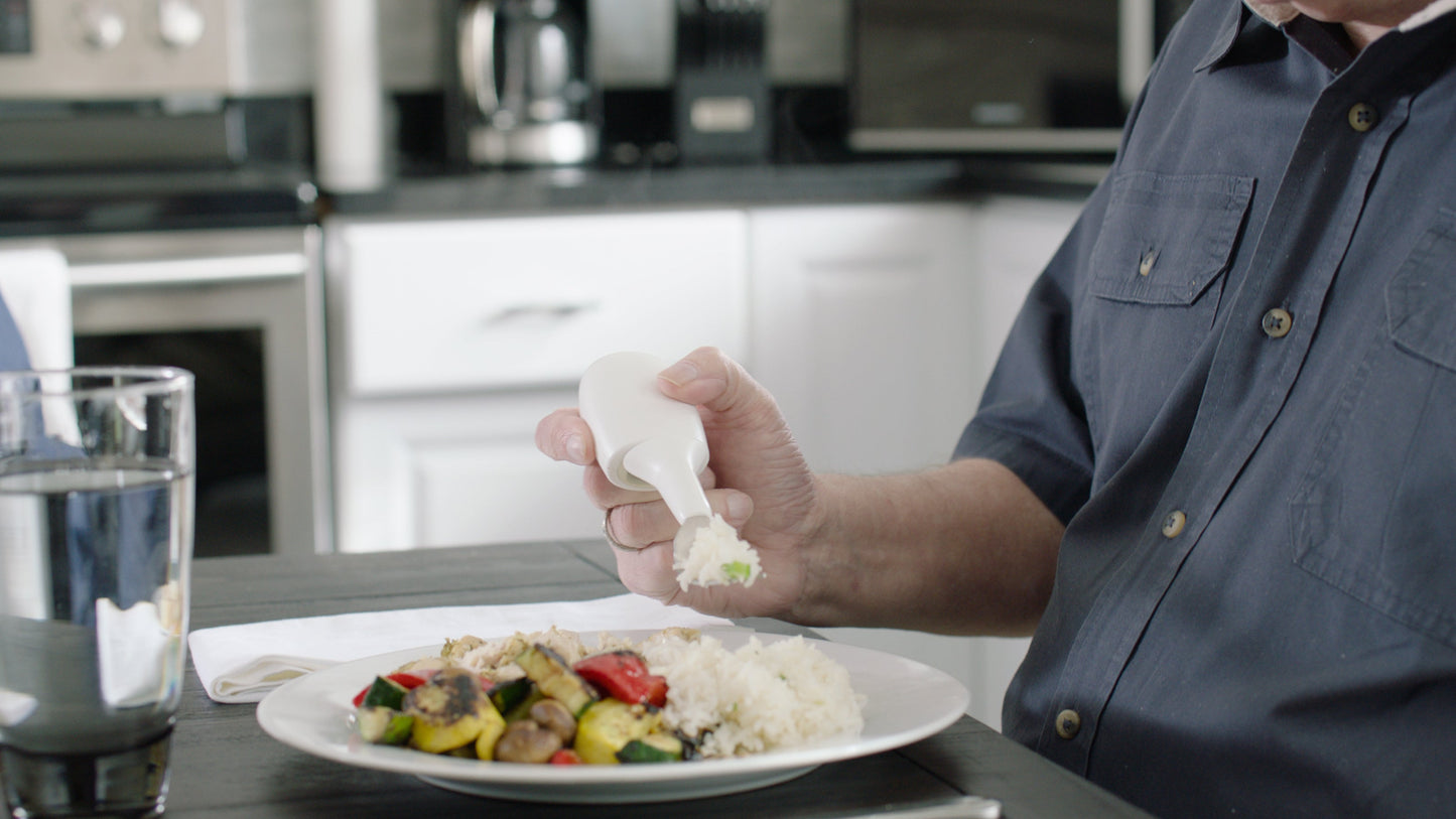 a hand holding Liftware steady with a fork attachmant, eating rice