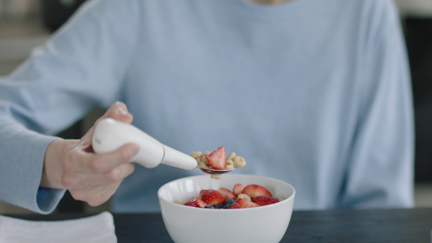 image of a hand holding the Liftware steady while eating cereal with barries